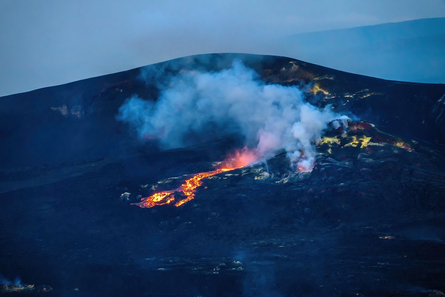 Lava oozes out of a volcanic vent discharging gas and steam