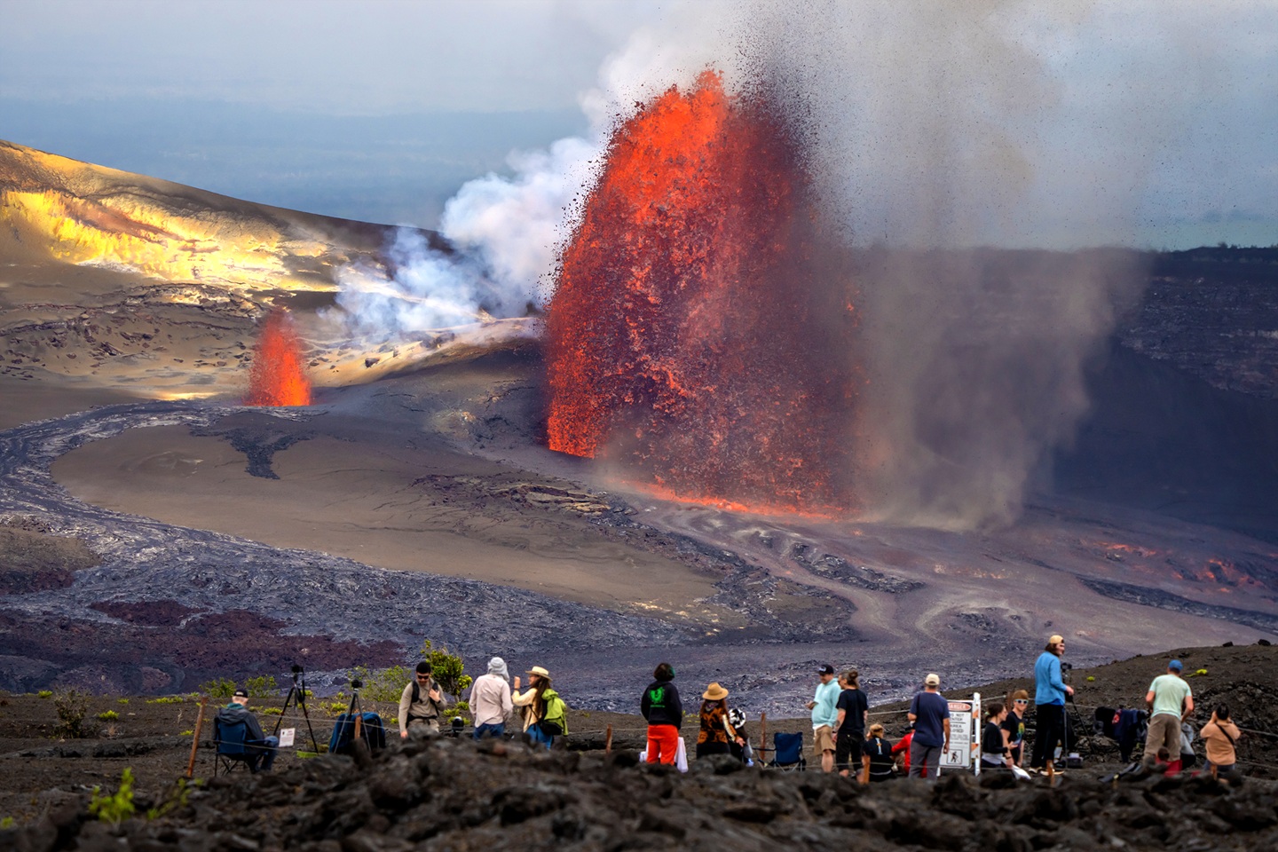 Visitors at an overlook watch a 600-foot lava fountain and a smaller vent erupting gas