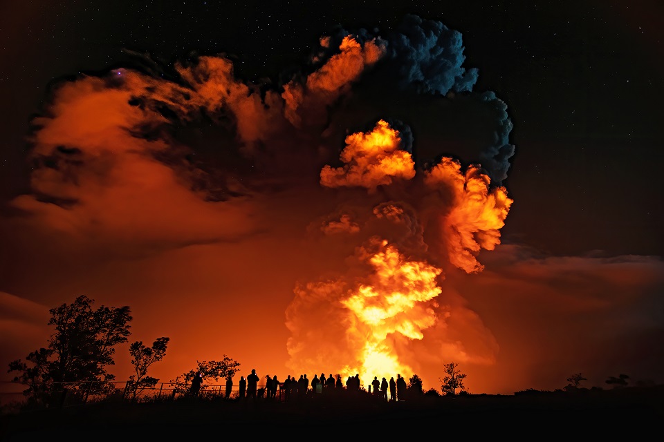 Silhouette of people with reddish lava reflection at night