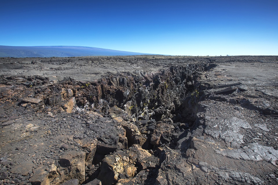 The Great Crack, with Mauna Loa in background. A deep earth crack in barren lava field