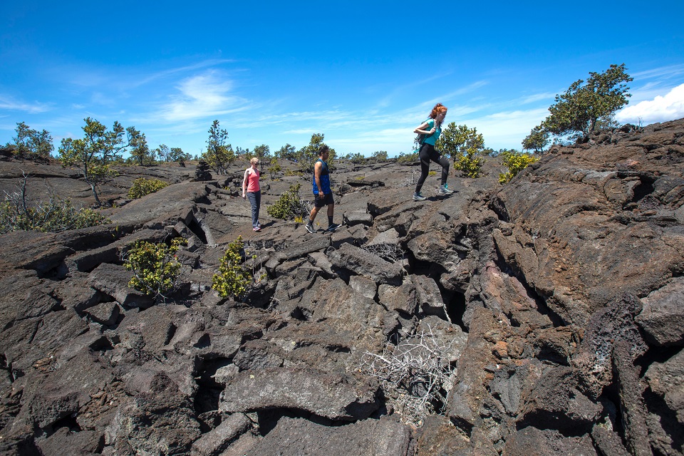 Hiking the 1868 lava flow from Mauna Loa in Kahuku Three hikers on a hardened lava rock trail