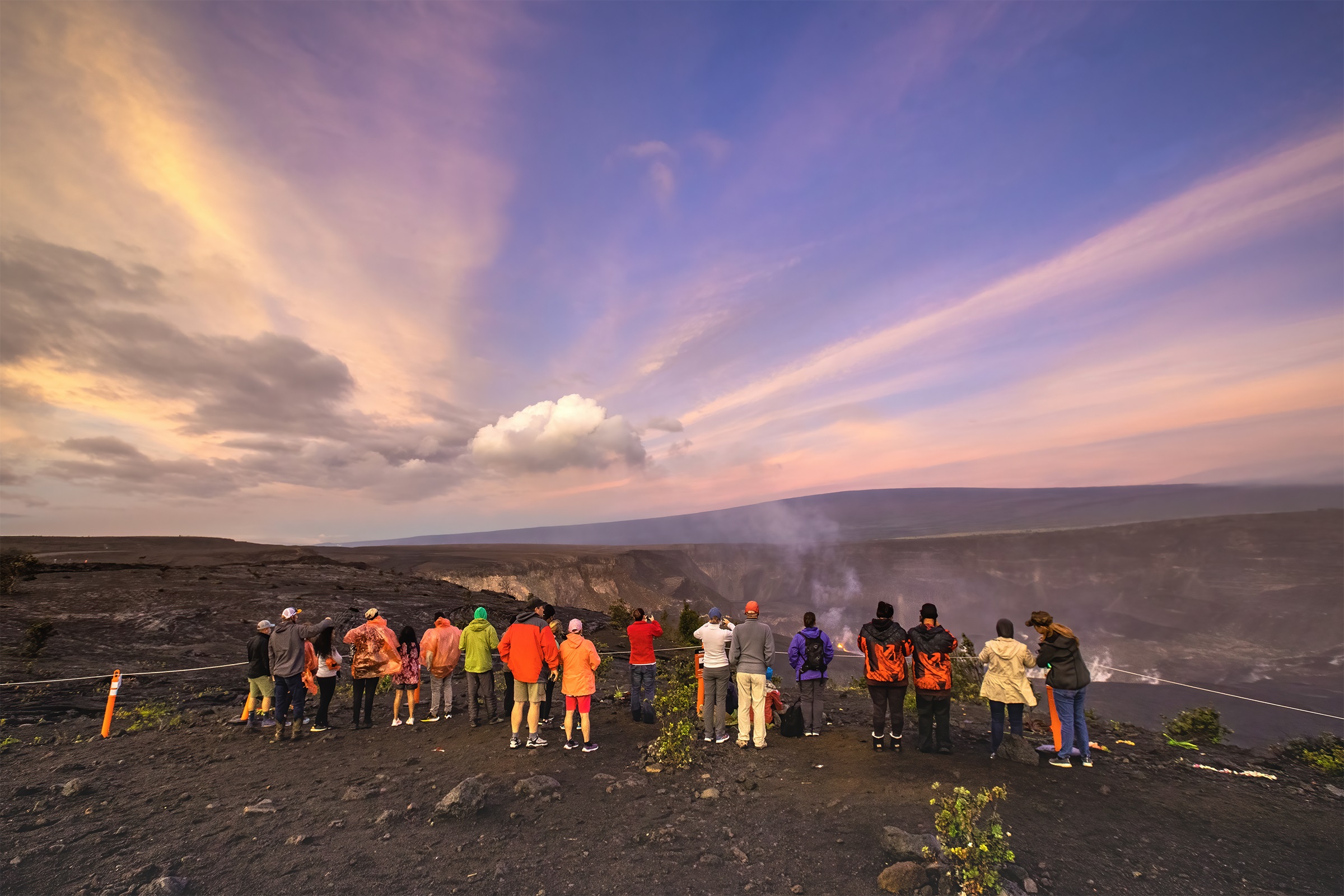People watch morning light illuminate a volcanic landscape