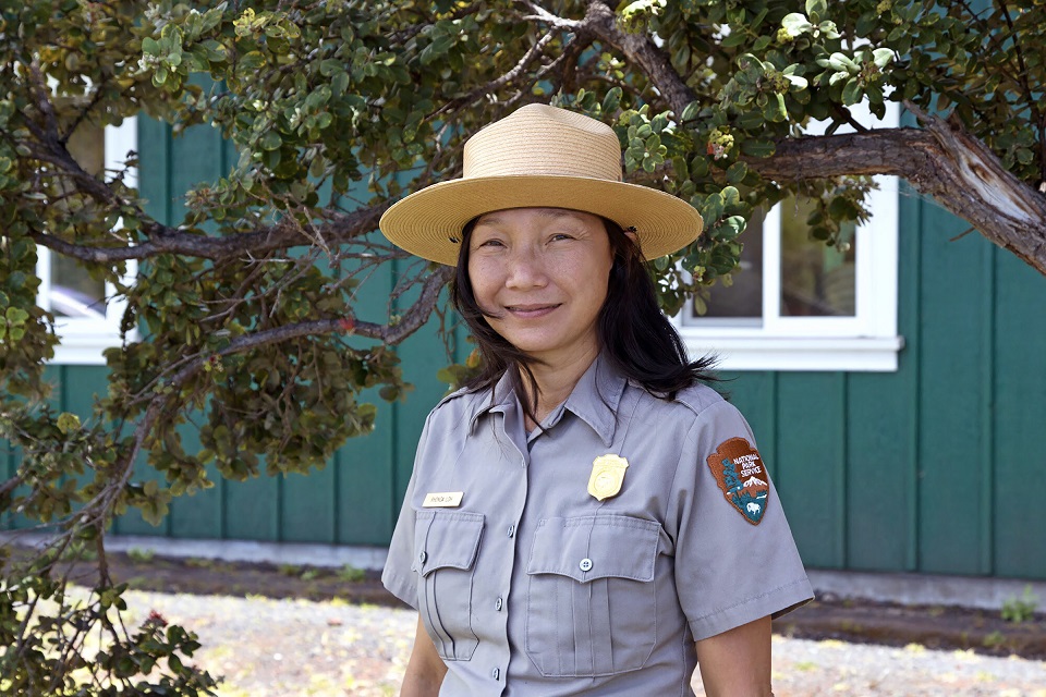 HVNP Superintendent Rhonda Loh Woman park ranger in uniform standing in front of a green building and tree