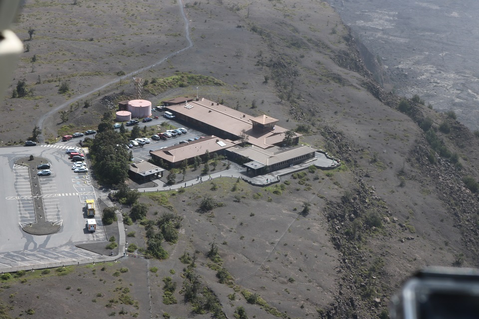 Aerial photo of buildings and a parking lot perched on the edge of a large volcanic crater