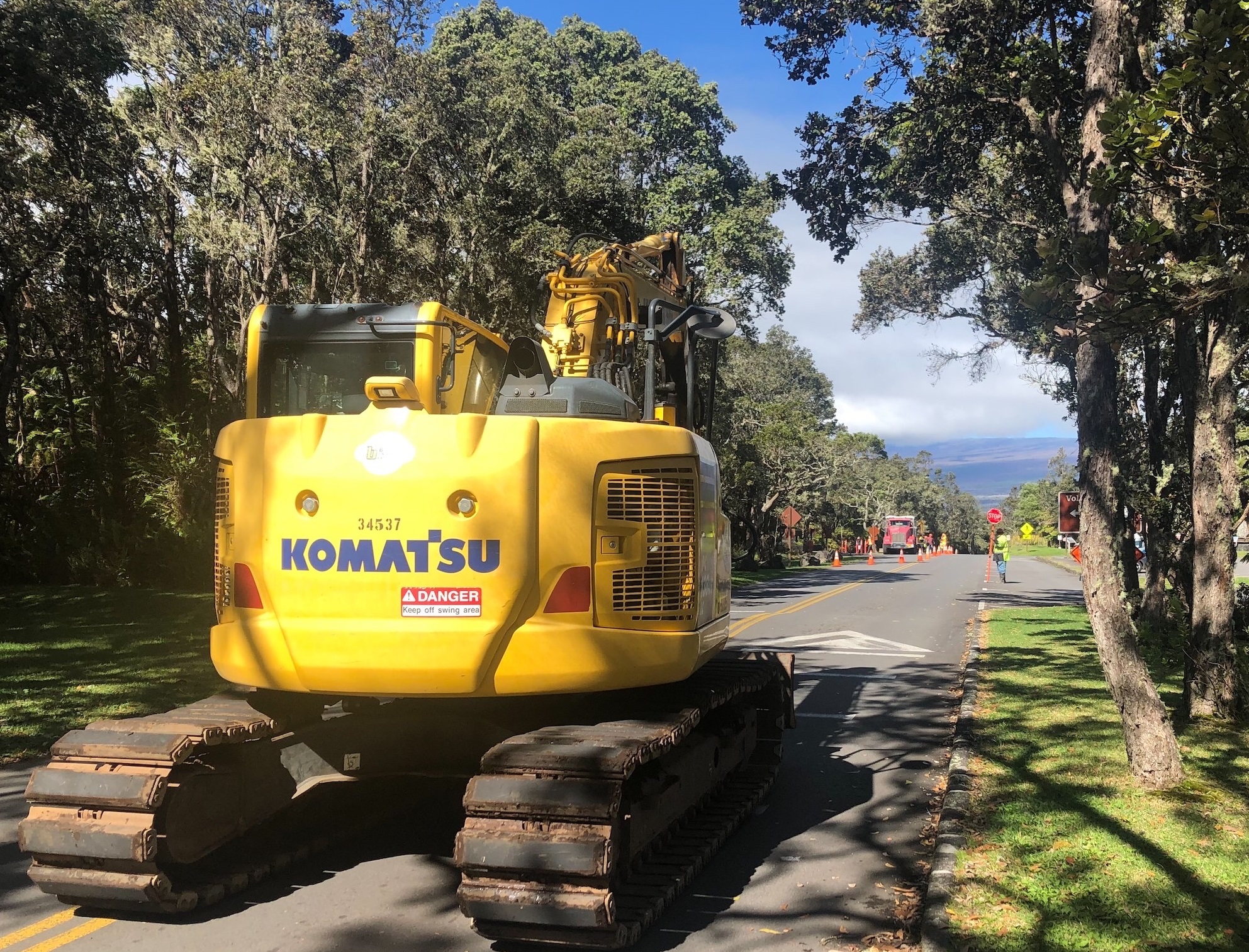 HAVO_Road work Crater Rim Drive_B.Hayes Large yellow front loader working on a road surrounded by trees
