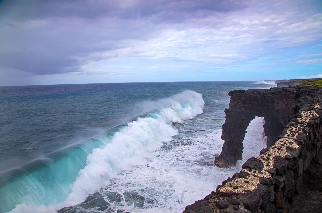 Waves crash into a sea arch.
