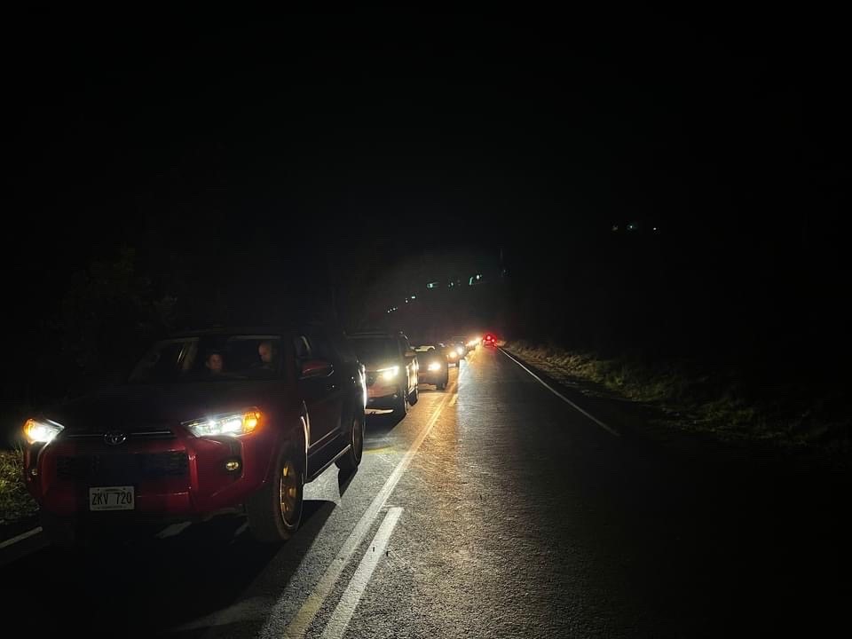 A line of cars on a road at night.