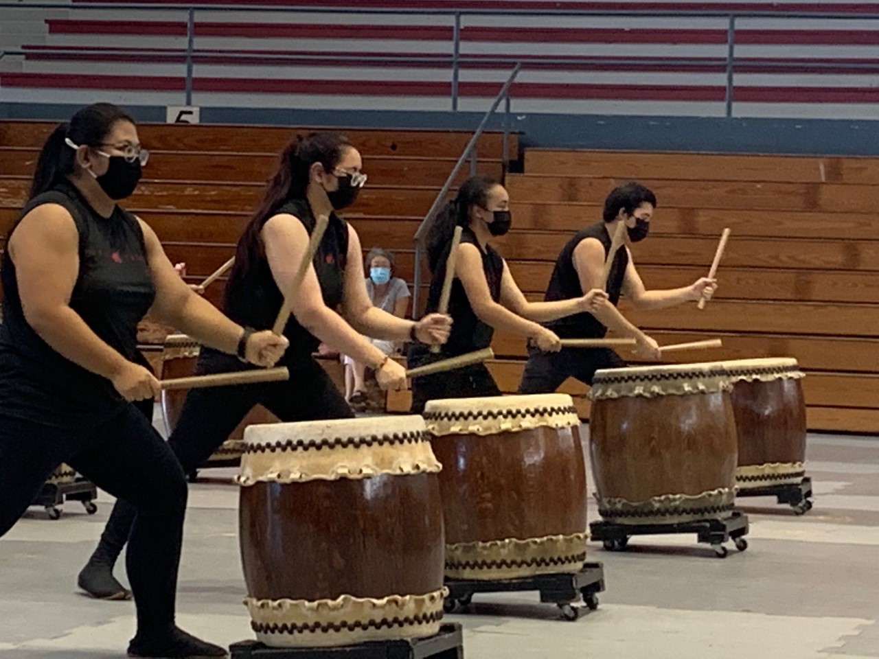 Puna Taiko drummers Drummers beat on large taiko drums in a school gym setting