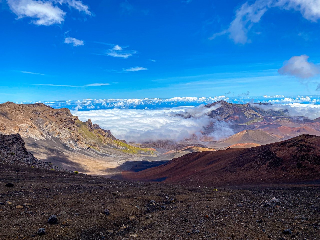 Jagged brown lava rock volcanic crater under blue skies and puffy white clouds