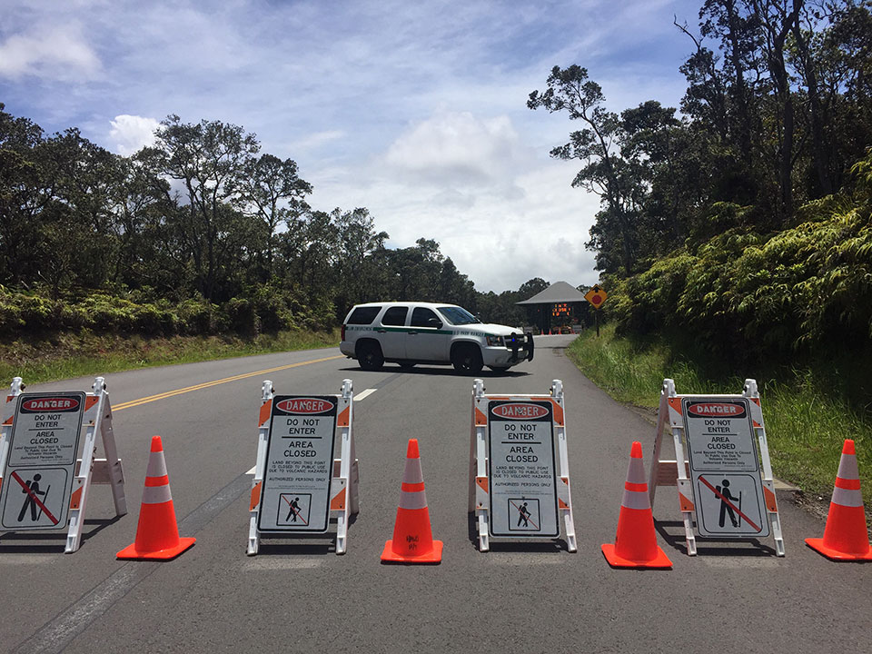 Photo of park entrance station with closure signs and NPS Law Enforcement