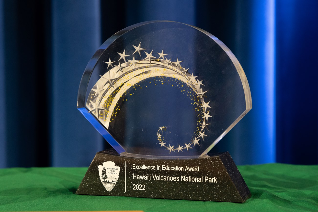 Glass award on table that reads "Excellence in Education Award Hawaiʻi Volcanoes National Park 2022".