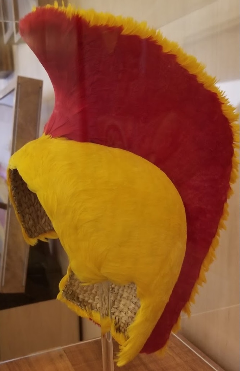 Replica of a traditional Hawaiian helmet with bright red and yellow feathers