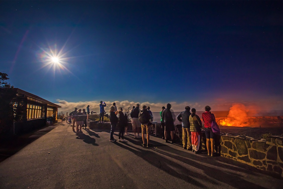Visitors gather under moonlight to watch a volcano erupti