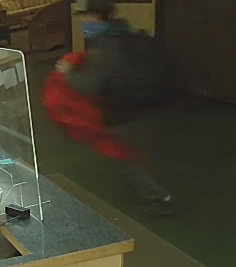 Male on surveillance camera Image of a man in a ball cap carrying a large object
