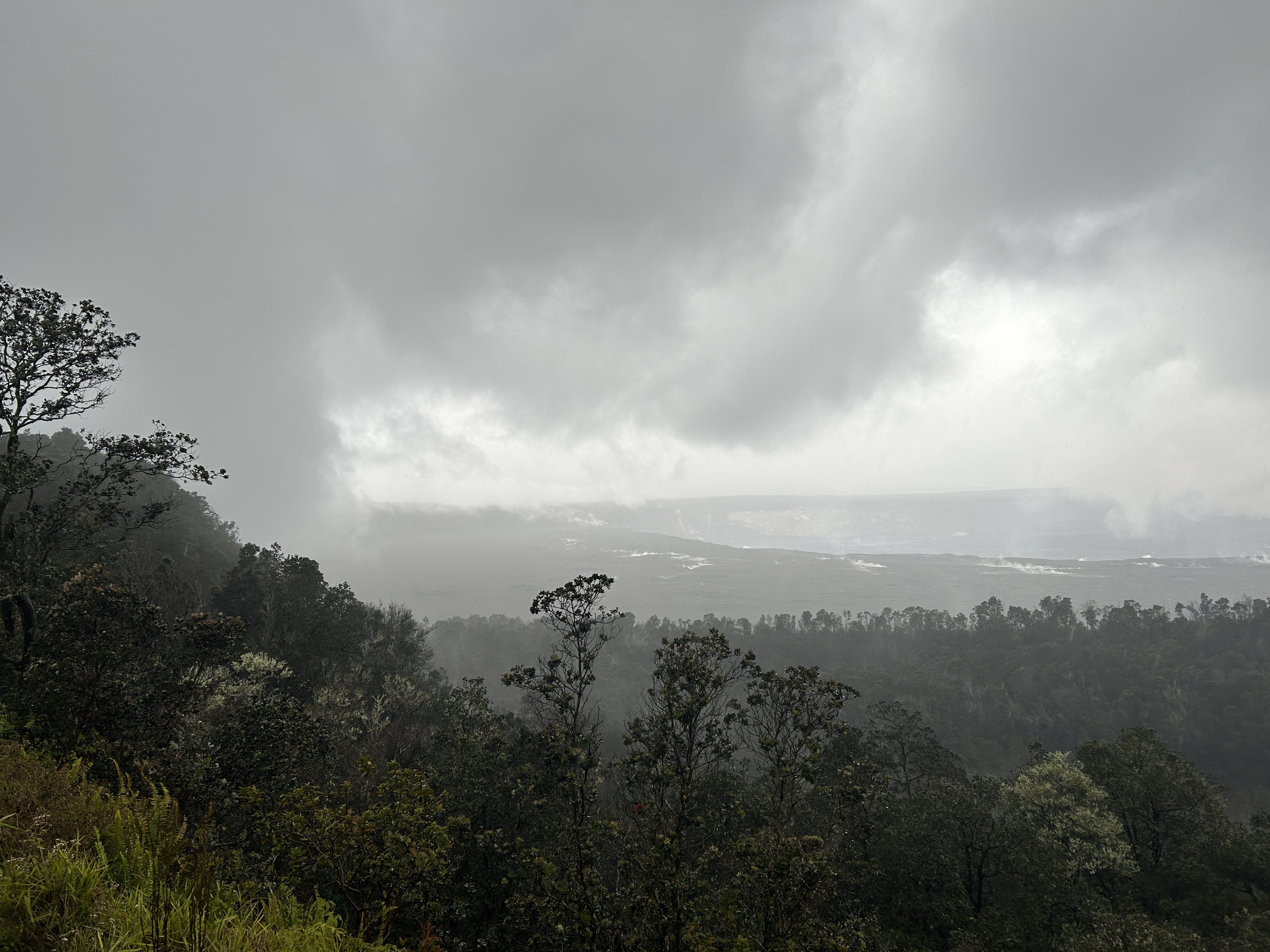 Clouds and fog obscure the skyline above a volcanic crater