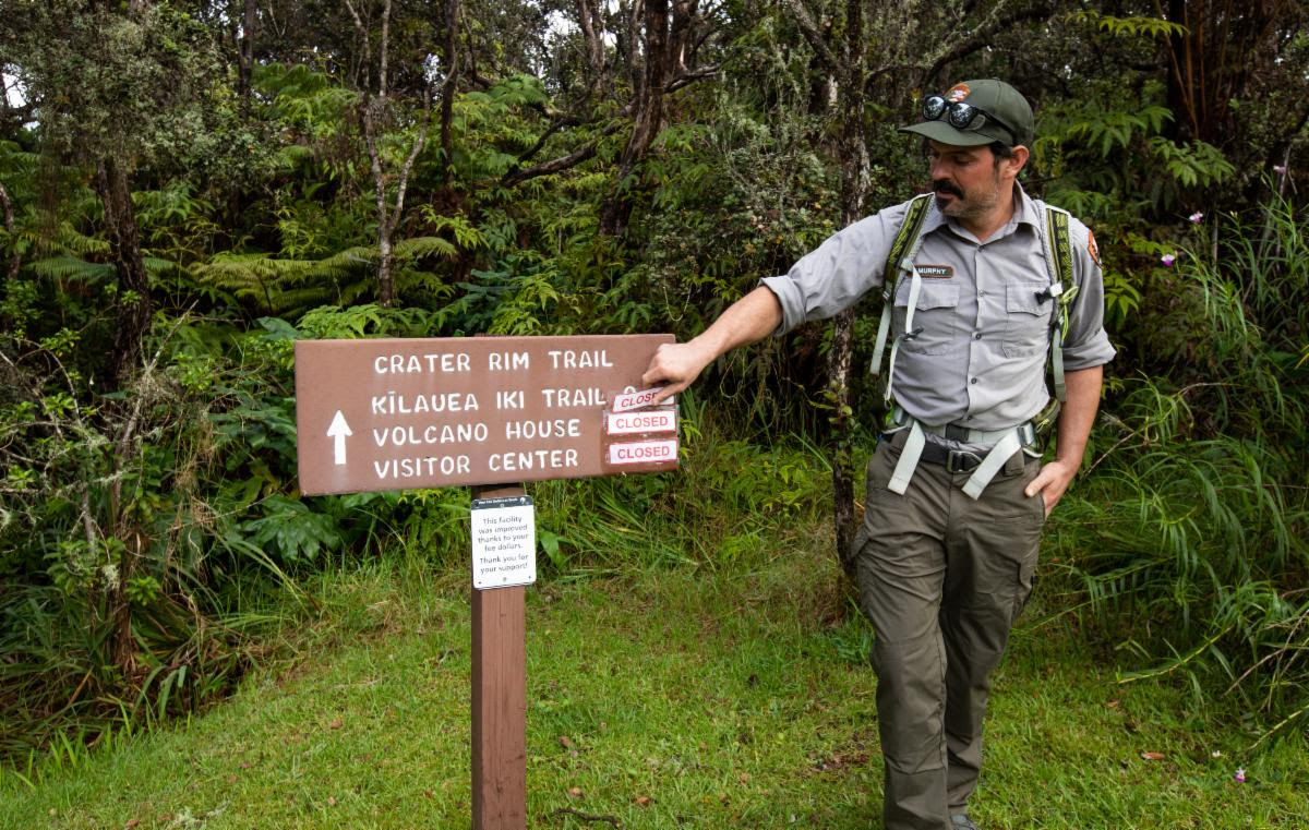 A trail crew member removes a closed trail sign