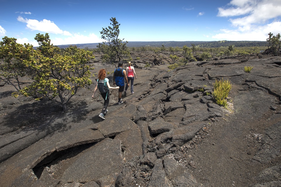 Three hikers on an old lava flow with short vegetation nearby
