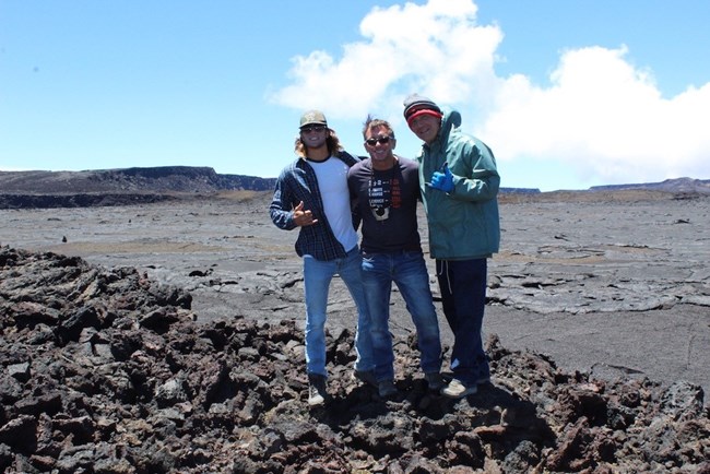 Three hikers posing in front of a volcanic crater