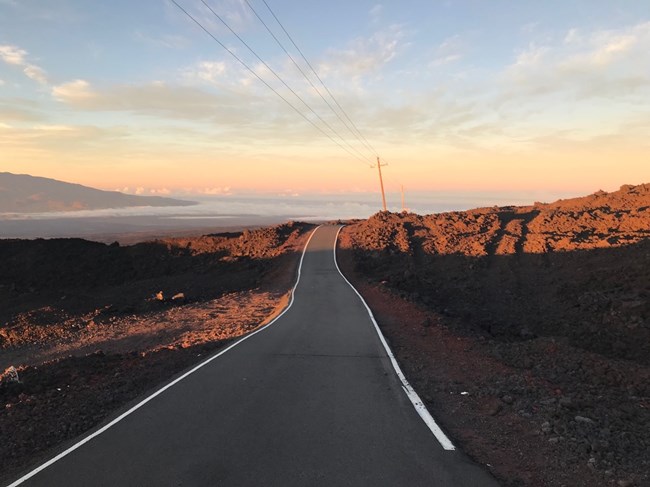 A paved road through lava fields at sunset