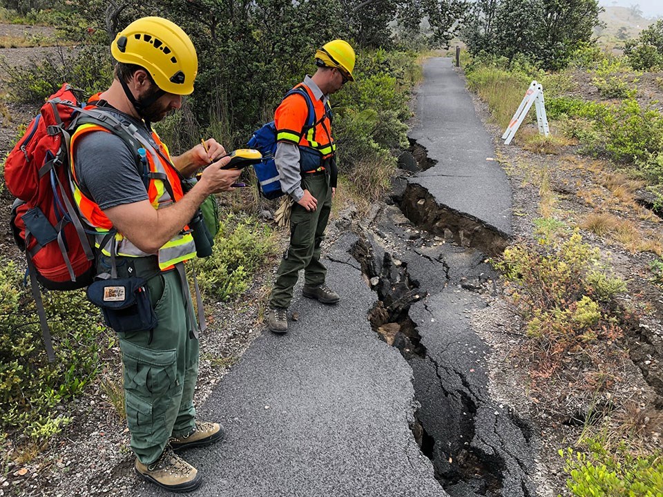 Rangers accessing trail damage near a crack.