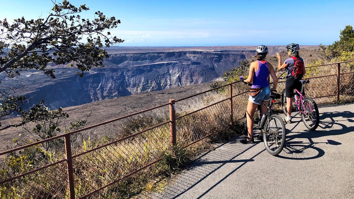 Two female bicyclists at an overlook of a volcanic caldera