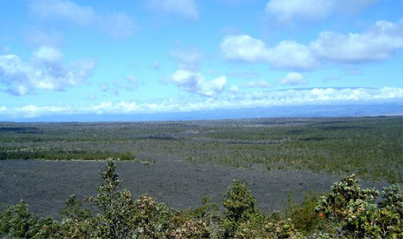 Mauna Loa, one of the main shield volcanoes, is seen to the west, partly mantled in clouds