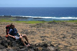 Drew is sitting down and resting along the trail, overlooking Kaaha