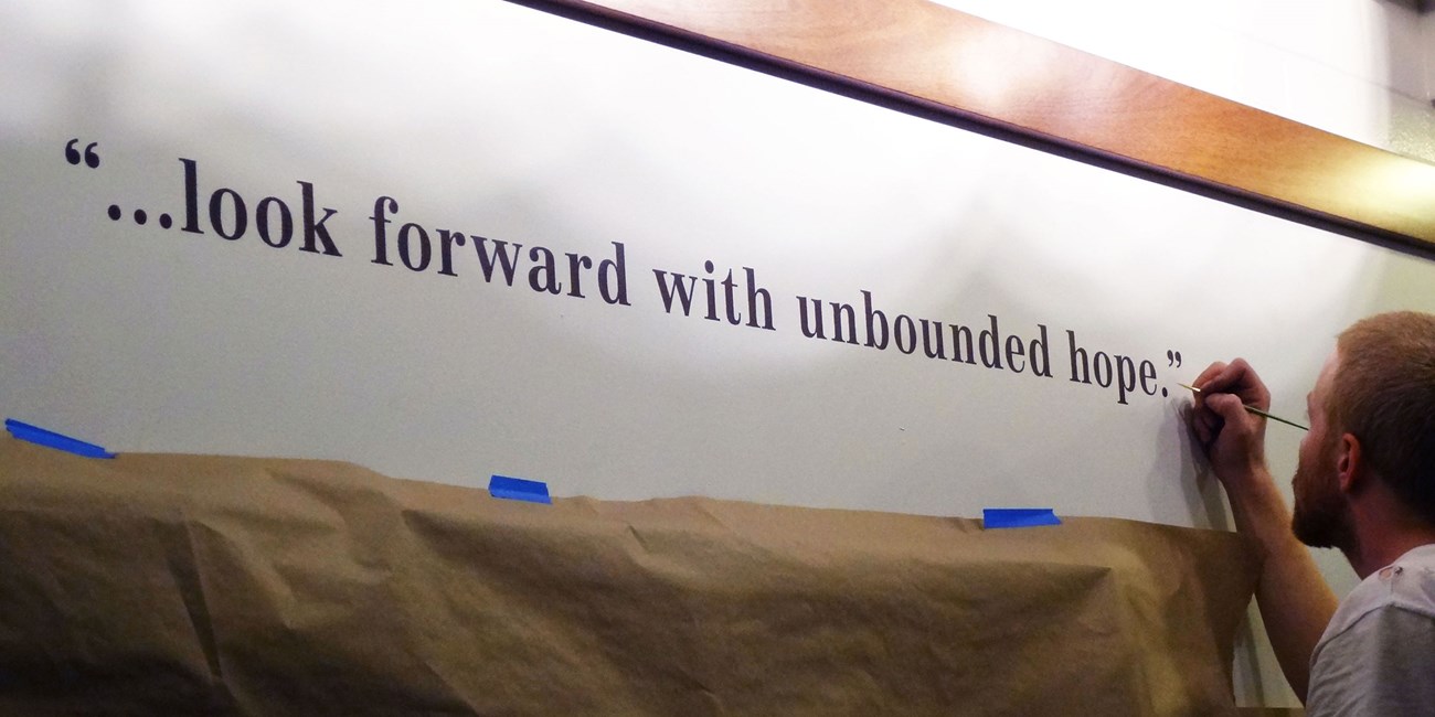 An exhibit contractor touches up stenciled lettering while installing a new exhibit at the visitor center in 2013.