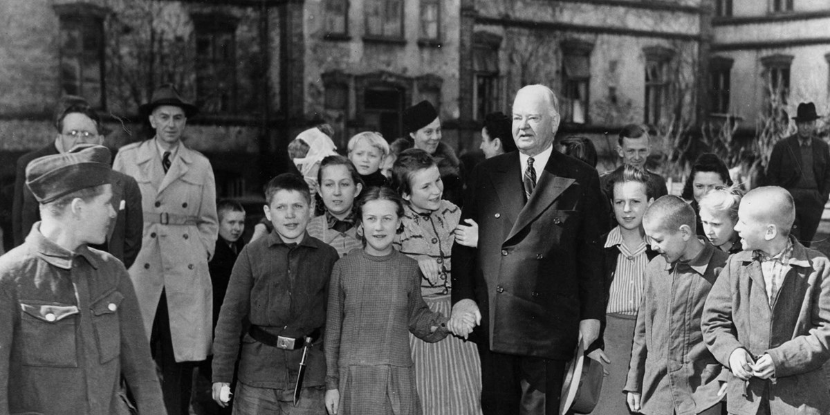 Children walk with and admire an elder former president in postwar Warsaw. Children walk with and admire an elder former president in postwar Warsaw.