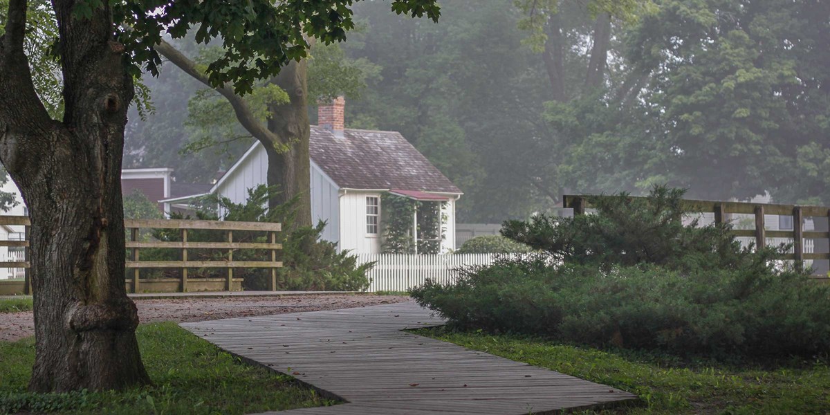 Walkway to Hoover's Birthplace A wooden boardwalk zig-zags over a bridge leading to a small white house.