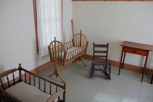 Antique rocking chairs and cradles furnish a small room.