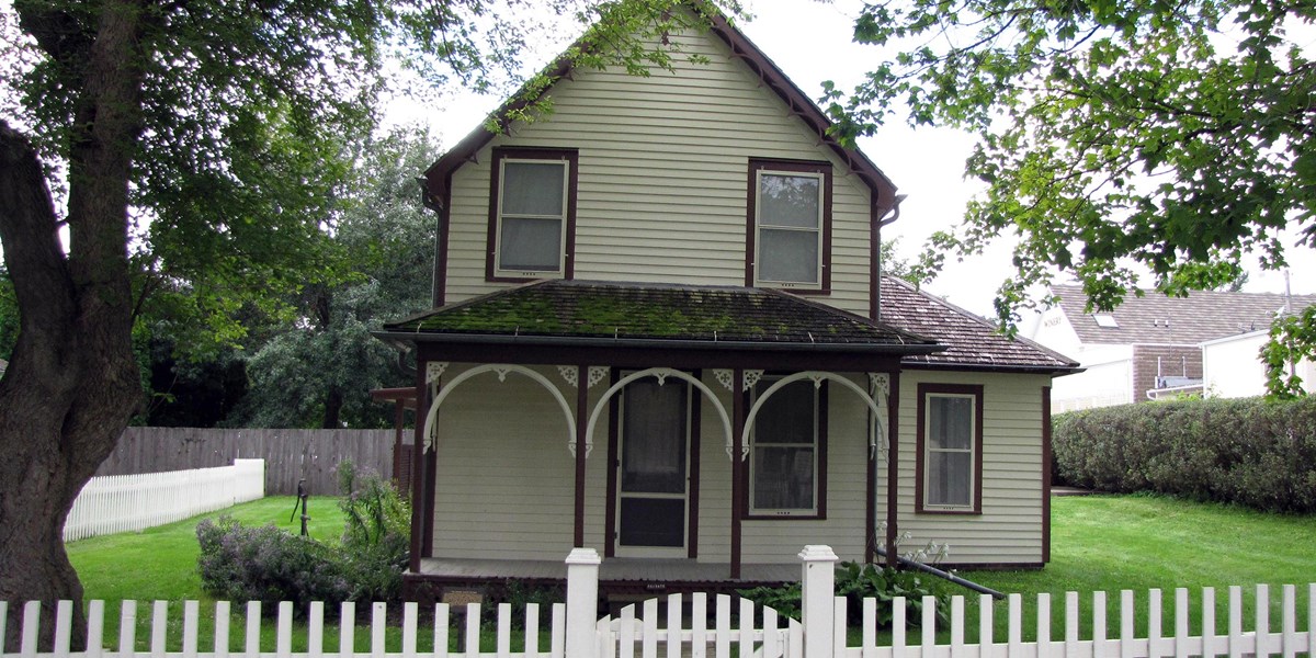 A yellow two story house has brown trim and Carpenter Gothic gingerbread on its front porch. A yellow two story house has brown trim and Carpenter Gothic gingerbread on its front porch.