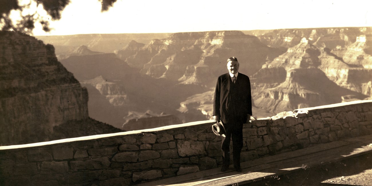 A man poses at an overlook of Grand Canyon in a 1928 photo.