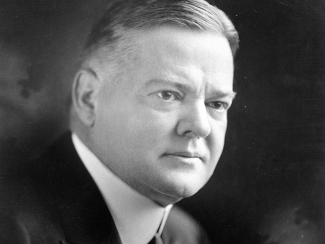 Herbert Hoover in 1928 A middle aged man in a suit, tie, and high-collar shirt sits for a portrait photo.