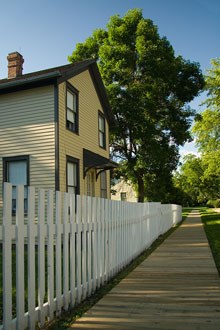 A boardwalk and picket fence near a historic home. A boardwalk and picket fence near a historic home.