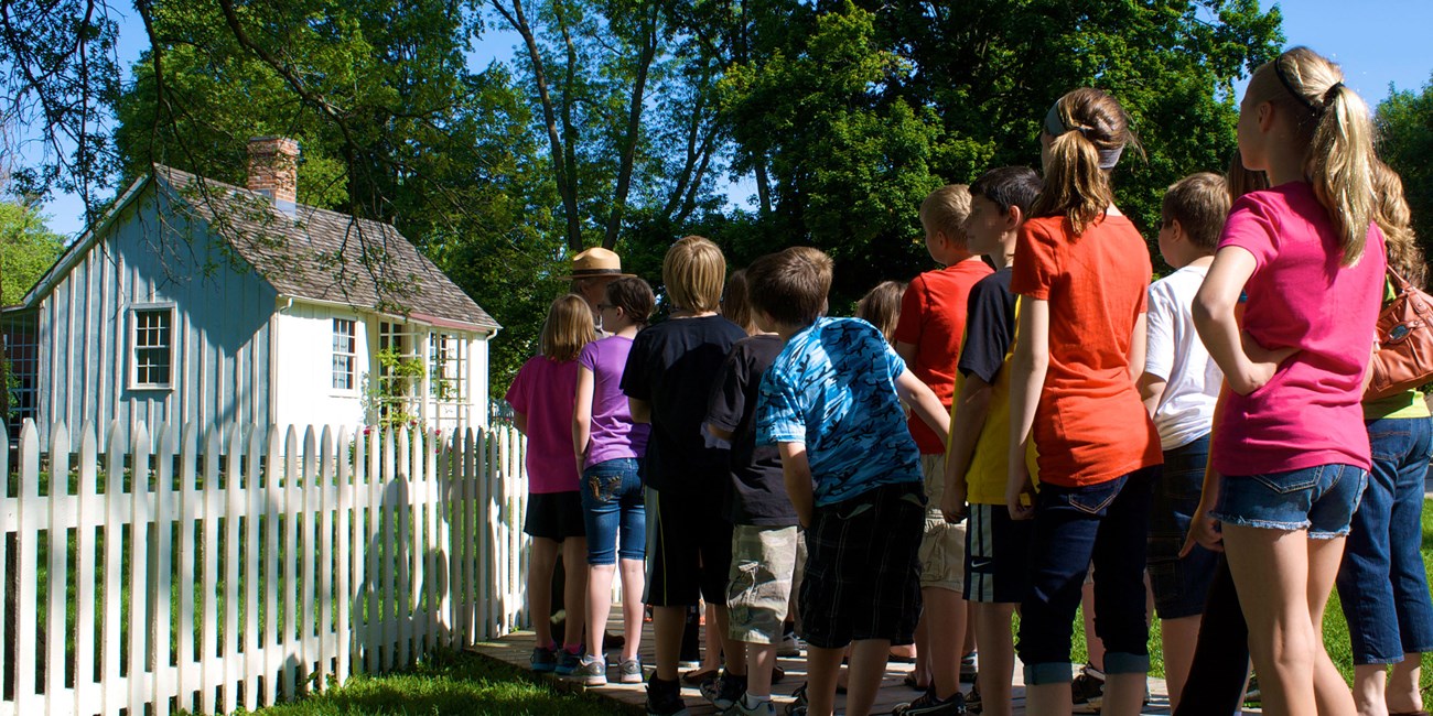 A park ranger talks to school children at a historic cottage.
