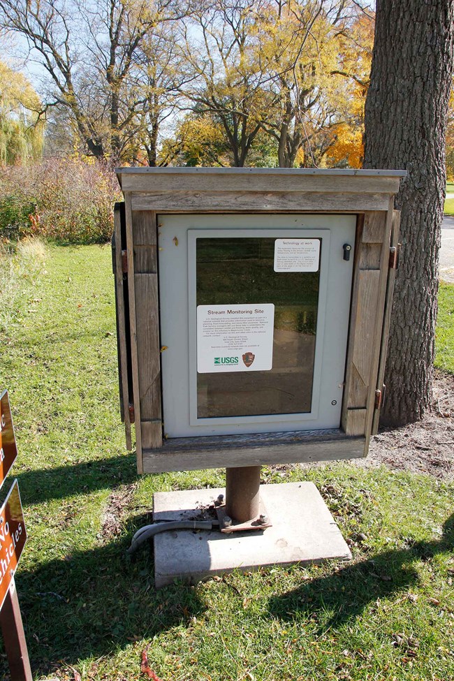 A wooden box encloses stream monitoring equipment.