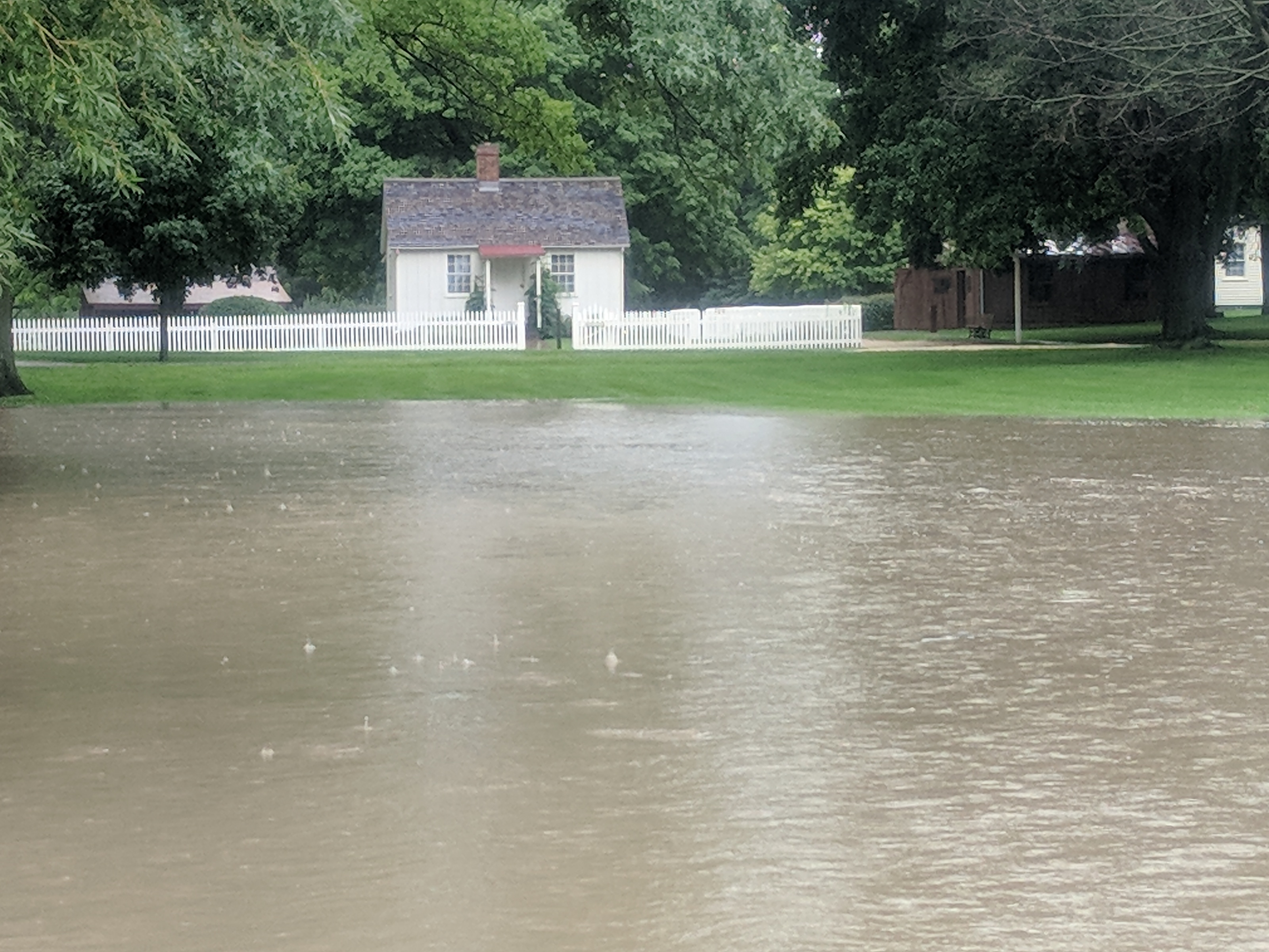 Small white house where Hoover was born in background with water from flooded hoover creek in foreground Small white house where Hoover was born in background with large amount of water from flooded hoover creek in foreground