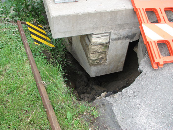 Roadway damage caused by erosion exposes part of a bridge.