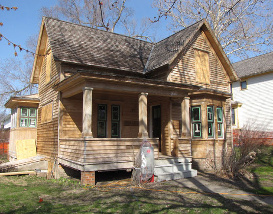 An unpainted two-story frame house.