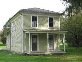 A green two story house with white trim and a porch. A green two story house with white trim and a porch.