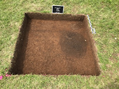 A large square pit in the ground marked by a pink string perimeter