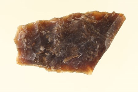 A four-sided piece of brown, opaque flint rock with jagged edges all around