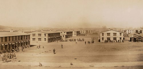 Several two-story buildings with several men walking around the landscape