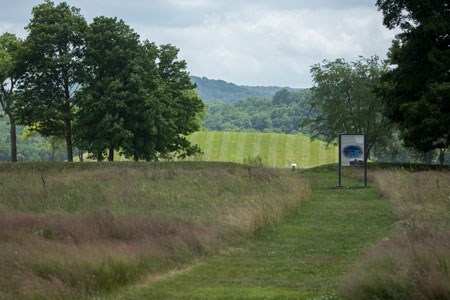 A trail cut through the grass leading to a large grass-covered mound