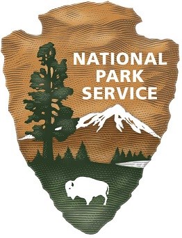 NPS Arrowhead showing a bison, trees, a mountain and a lake on an arrowhead shape.