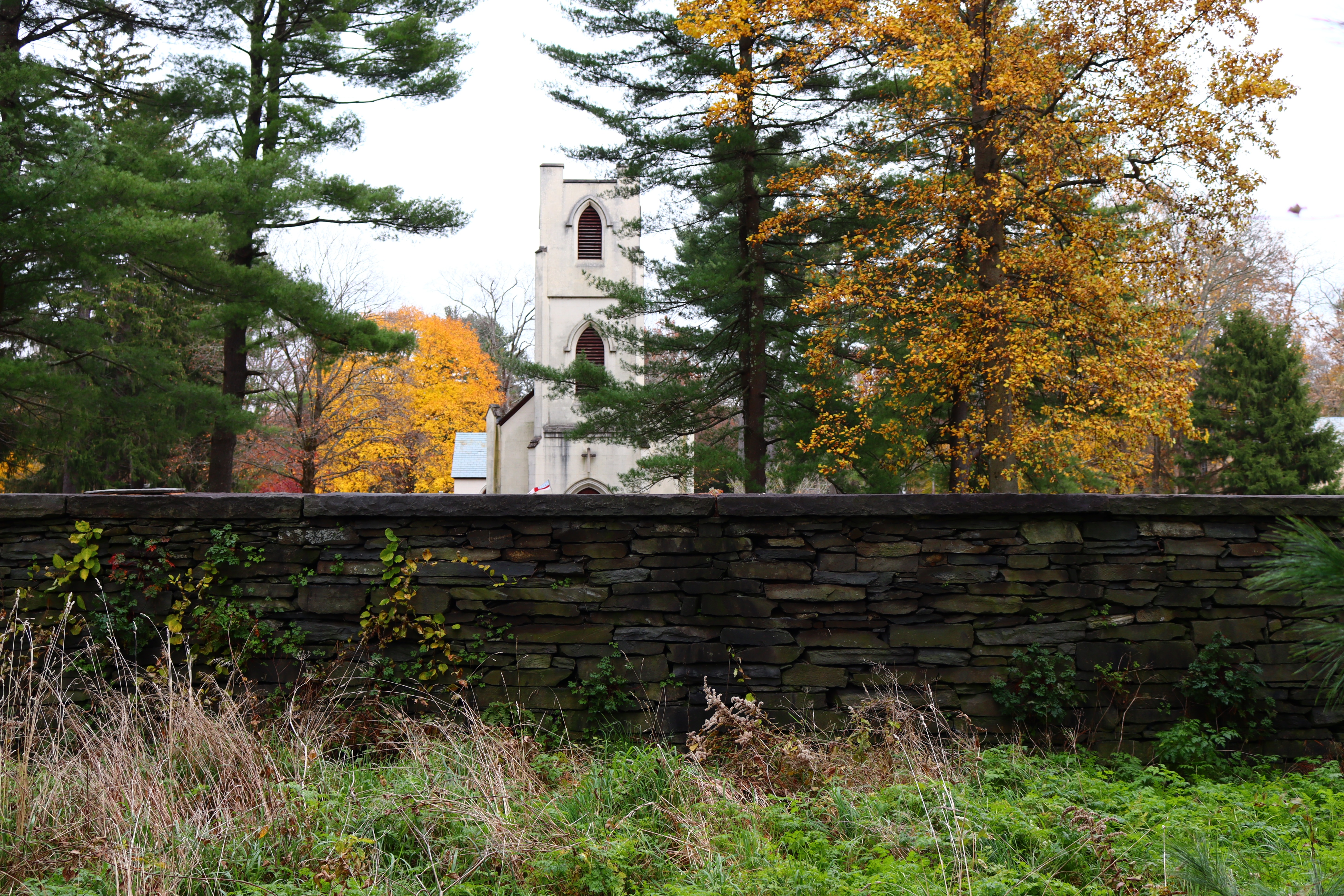 Stone wall along Albany Post Road A stone wall with a church and trees behind it