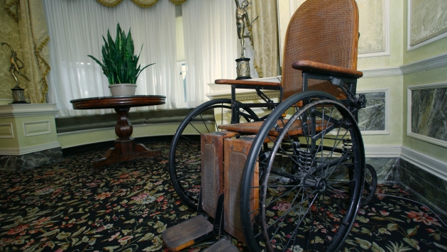 A wood and leather wheelchair with arched back used by FDR