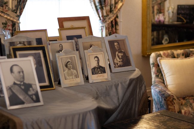 A group of silver framed portraits of royal persons displayed on top of a grand piano.