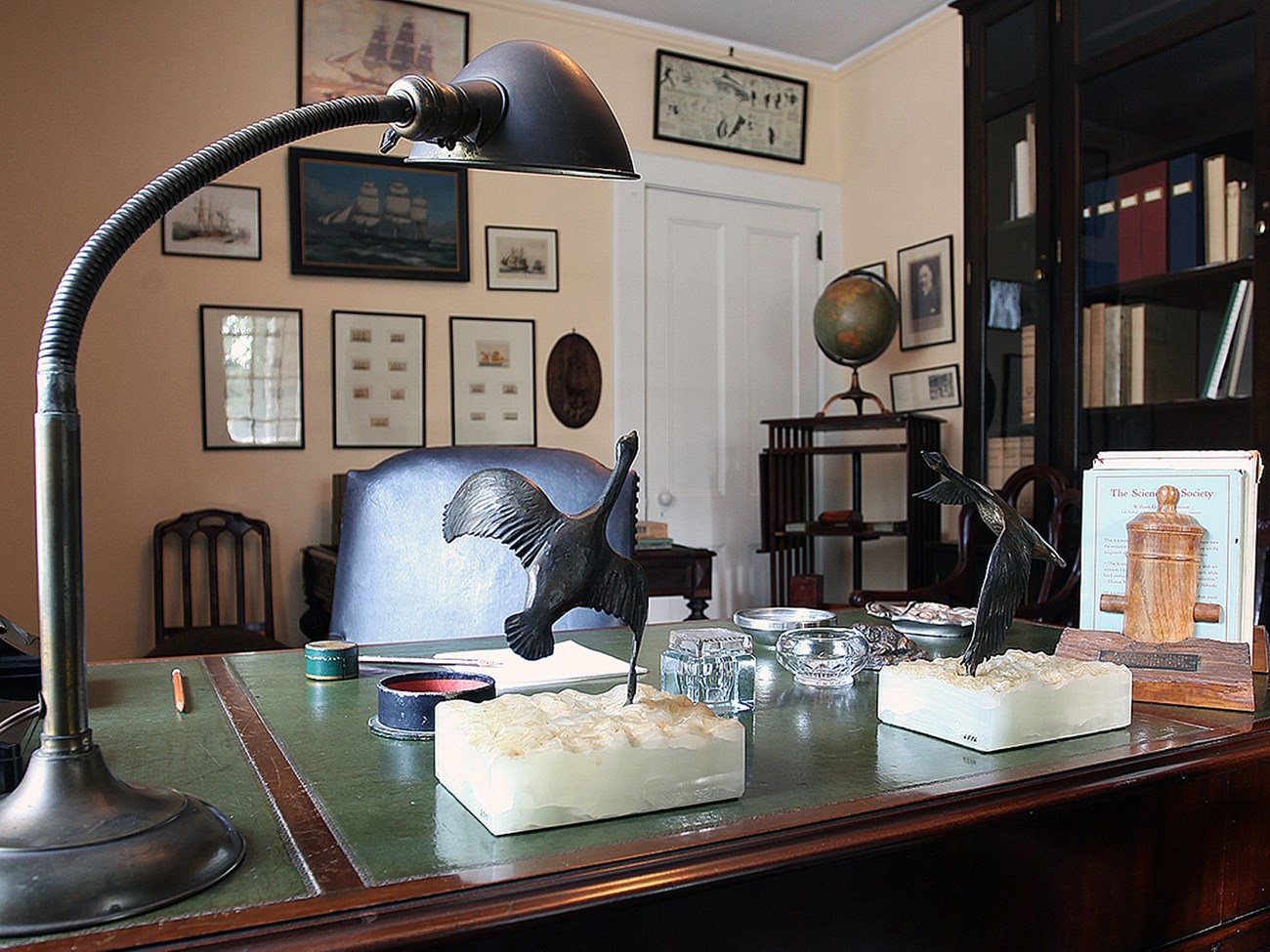 A small room with desk and framed prints on the wall.